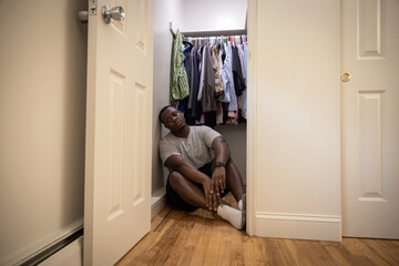 Fototapeta na wymiar Sad and depressed man in anxious state in bedroom on the floor