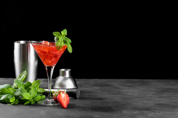 Cold summer strawberry cocktail mojito, margarita, daiquiri in a martini glass. Fresh strawberry drink with ice, bartender tools set and mint leaves on dark background. Iced strawberry lemonade