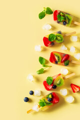 Fruit ice cream, colorful summer dessert on stick with strawberry, blueberry, kiwi and mint leaf