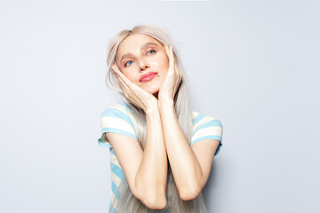 Portrait of beautiful blonde girl holding hands on face, on white background.