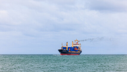 Fototapeta premium container cargo ship sailing in green sea to transport of goods import export internationally or worldwide as business and industrial transport and marine services in open sea cloud sky background,