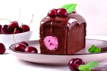 Chocolate cake with cherry cream filled center and topped with glazing, berries and waffle leaf. Exquisite dessert served on the plate