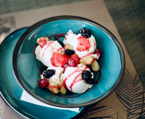 Vanilla ice cream balls on author's ceramic plates. Creamy ice cream with syrup and various fresh summer berries. Strawberry. Blackberry white and black. Gooseberry. Summer delight.