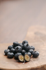 Fresh blueberries on wood board one berry is cut in halves