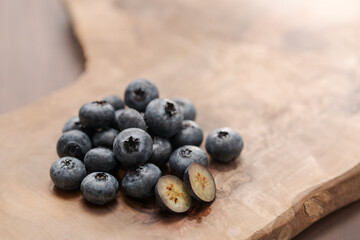 Fresh blueberries on wood board one berry is cut in halves