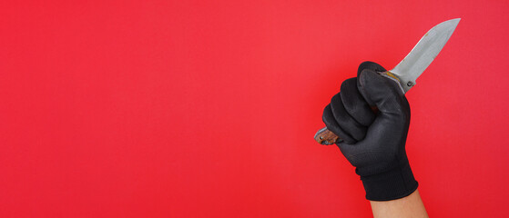 hand wearing black gloves hold wooden folding knife isolated red background 