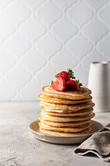 Stack of pancakes with strawberries with napkin on textured background with copy space. Homemade breakfast concept