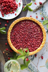 Open almond tart with wild strawberries on a table with a tablecloth. Homemade cakes with hand-picked seasonal berries. 