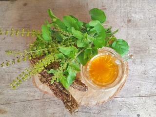 Tulsi tea is served in a cup with fresh leaves on the side of the selected focus.