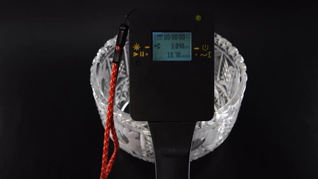 Man hand use homemade dosimeter of ionizing radiation. Overdose in the old Soviet crystal vase. Concept of dangerous objects at home. assessment of particle level indicators.