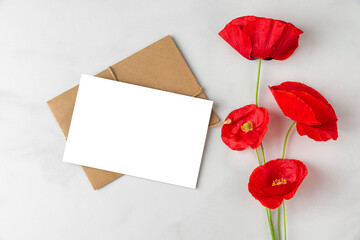 Red poppy flowers with blank greeting card and envelope on white background. Wedding or holiday invitation