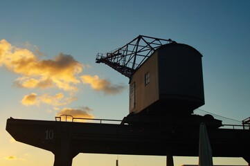 Silhouette of an old harbour crane at Osthafen Frankfurt, Germany against the winter sunset.