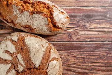 Two loaves of crusty bread on rustic wooden table.
