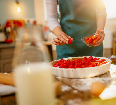 Closeup. Young woman making a strawberry pie, in the kitchen. the sun enters through the window