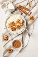 Top view of creamy rice pudding or porridge whith milk, cinnamon powder and walnuts for breakfast. Serving or kheer recipe  with milk and additives.