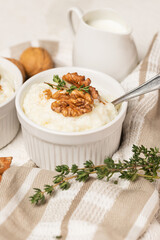 White rice pudding mold, whith milk or cream, cinnamon, whole walnuts and thyme stems on striped napkin. Serving a kheer