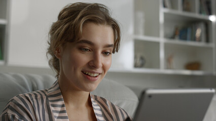 Portrait smiling woman reading good news holding tablet computer at home.