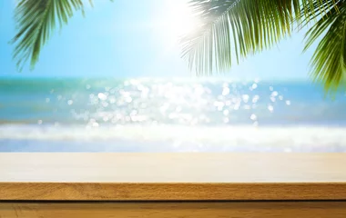 Foto auf Glas Leerer Holztisch über unscharfem sonnigem tropischem Strandhintergrund. Outdoor-Party-Mock-up für Design und Produktpräsentation. © Konstiantyn