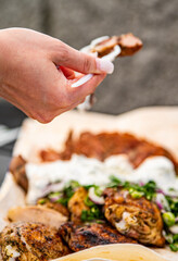 woman hand holding plastic fork with meat and sause outdoor