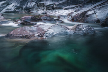 Atmosph&auml;rischer Naturhintergrund mit riesigen Steinen im Bergfluss. Gro&szlig;e Felsen im m&auml;chtigen Wasserstrom, Nahaufnahme. Naturhintergrund mit Wald. Dunkel t&uuml;rkisblauer Fluss mit Steinen.