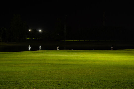 Beautiful dark night view of the golf course, Bunkers sand and green grass, garden background In the light of the spotlight underexposure view. Film camera look photo noise and Grain.