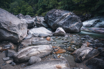 Atmosphärischer Naturhintergrund mit riesigen Steinen im Bergfluss. Große Felsen im mächtigen Wasserstrom, Nahaufnahme. Naturhintergrund mit Wald. Dunkel türkisblauer Fluss mit Steinen.