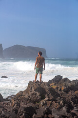 a man in green shorts looks at the ocean waves