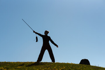 Asian woman with sword practicing taijiquan at sunset, chinese martial arts, healthy lifestyle...