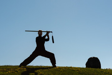 Asian woman with sword practicing taijiquan at sunset, chinese martial arts, healthy lifestyle...