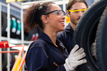 Multiracial mechanics at garage smiling while working. Mechanics checking tires stock. Car...