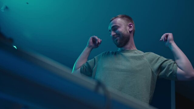 A music producer is dancing in a music studio. Electonic music.