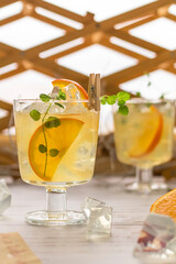 Summer cold lemonade with ice, orange and mint in transparent glasses with a cocktail straw. Refreshing homemade drink. vertical position.
