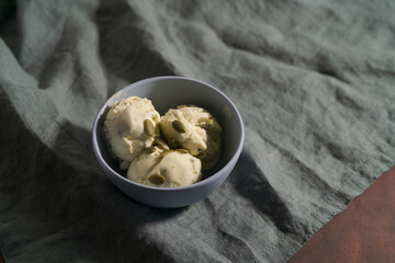 Pistachio ice cream with pumpkin seeds in bowl on table