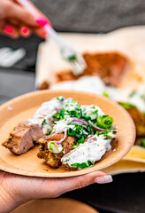 woman hand holding paper plate with meat and sause outdoor