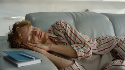 Relaxed guy sleeping sofa in pajamas closeup. Smiling freelancer enjoy daydream