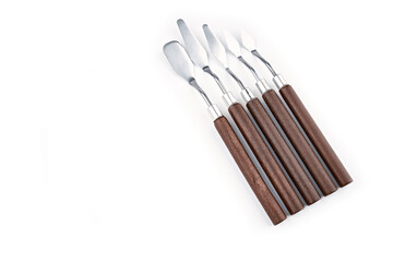 Art palette knives lie on a white art canvas. ainless painting palette knife with wooden handle. Palette knives, isolated on white. set new painting palette knives.