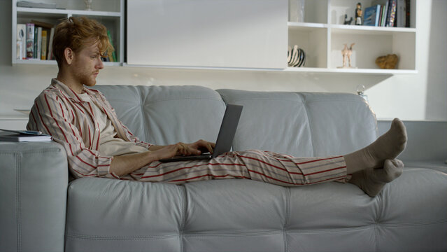 Man Working Home Office In Pajamas. Focused Ginger Student Using Laptop Computer