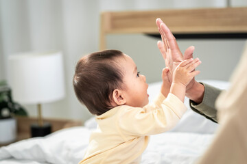 Asian baby girl with white skin and big eyes  naughty age  playing on the bed by the bedroom window