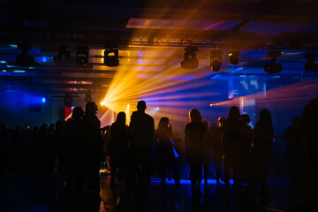 Corporate party event entertainment: yellow and blue spotlight or ray shines in the shadows of...