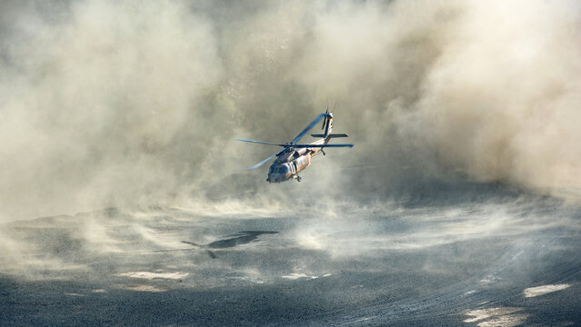 Military Black Hawk helicopter landing or taking off in dramatic clouds of dust