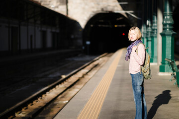 A woman is waiting for a train on an empty platform.