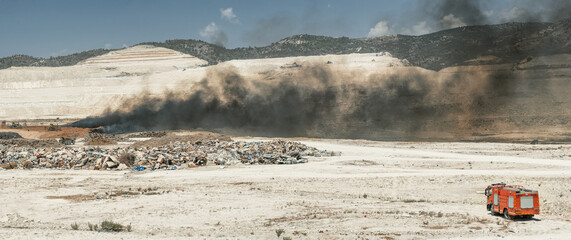 Fire fighting in a tire yard. Panoramic shot of garbage dump with fire truck and earth moving machinery