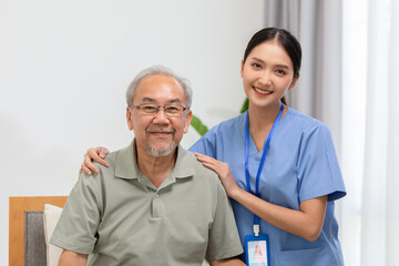 Happy caregiver and elderly patient smile and looking camera nursing at home. Asian senior man and doctor giving care and empathy to patient or retirement in homecare service. Elderly care concept