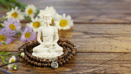 Obraz na płótnie Canvas Vesak, Buddha Day. Buddha statue, prayer beads and flowers on a wooden background with copy space. Asian spa ritual procedure and meditation. Energetic health and relax. Mental healing. Soft style