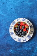 Vivid still life with summer berries on a table. Textured background with copy space. Fresh organic fruit on a table. Eating healthy concept. 