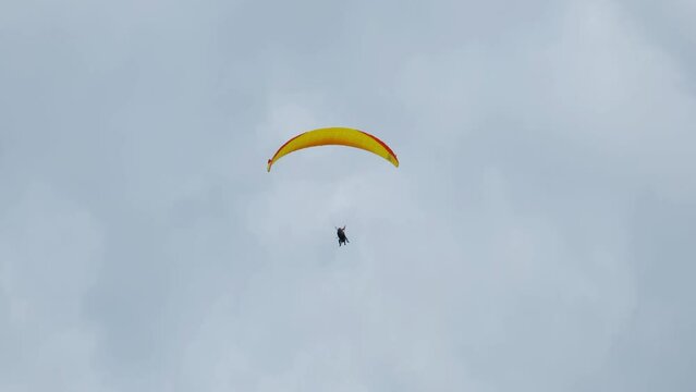 A handheld and follow focus with noise effect of flying paragliders in Interlaken before raining.