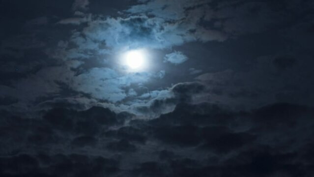 Nighttime Timelapse. The movement of clouds and the full moon in the night sky. Beautiful atmospheric video