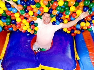 cheerful man lying in ball pit