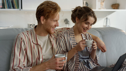 Joyful lovers watching laptop on comfy couch closeup. Romantic couple in morning