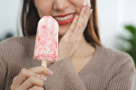 Asian Woman touching her chin feeling sensitive teeth when eating an ice cream. Have a gum and oral problem.